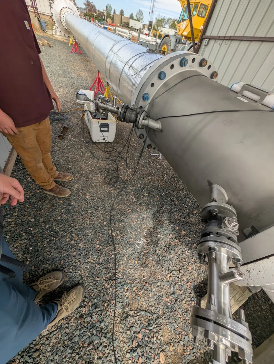 Lab technician at the ultrasonic flow meter on the CEESI test line with transducer insertion mechanisms, preamplifier cables and pressure instrumentation connected