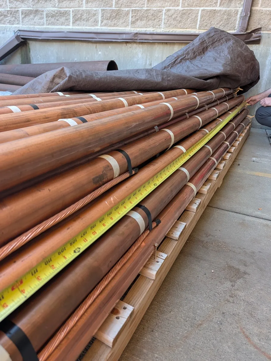 Tape measure laid along copper Chem-Rod grounding electrodes to verify length during dimensional inspection