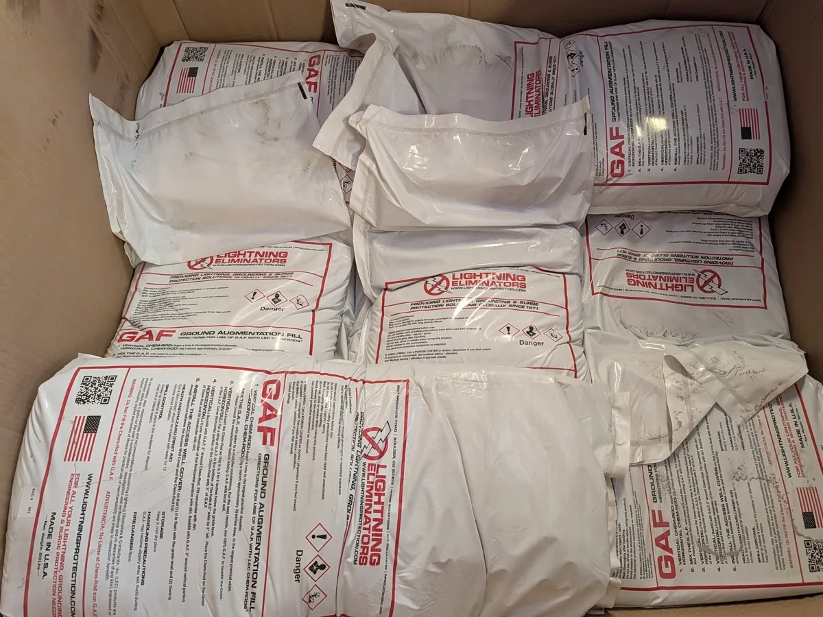 Bags of Ground Augmentation Fill packed in a carton with hazard pictograms and net weight on the label