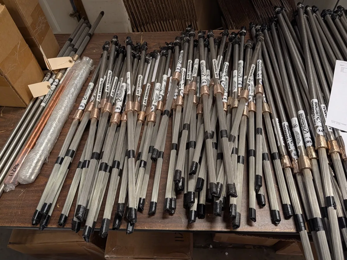Spline ball air terminals with brass ferrules and bundled stainless steel splines laid out on a bench, labels being checked