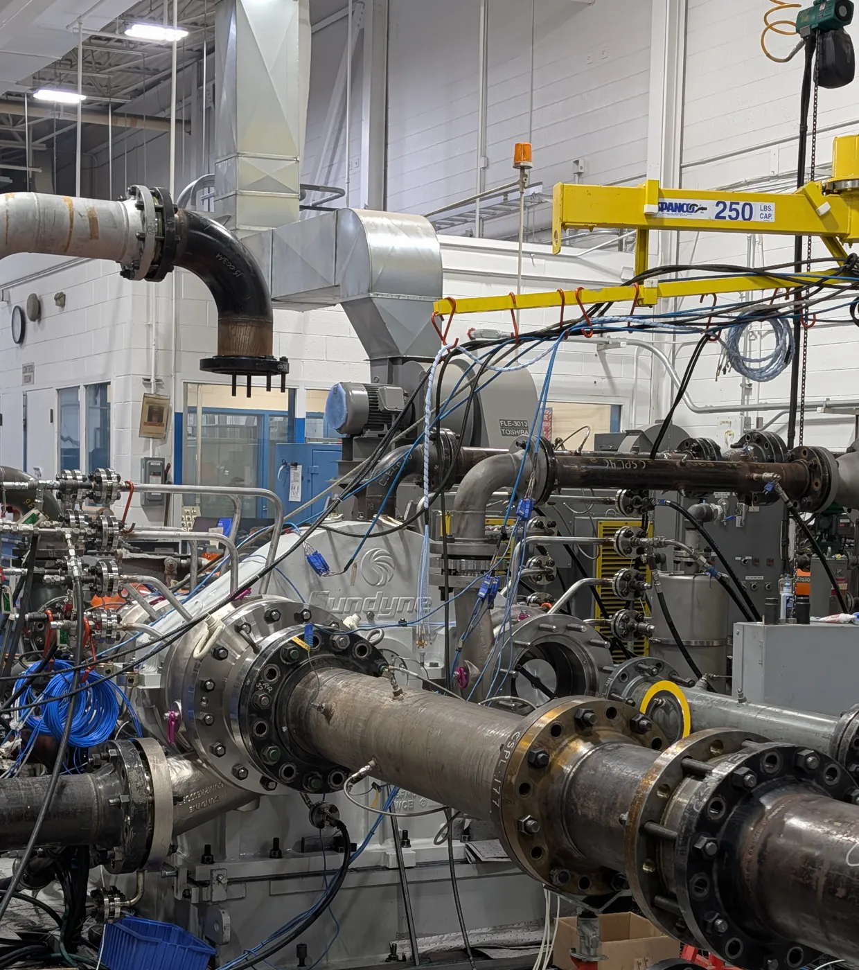 Integrally geared centrifugal compressor on the test bed, connected to test loop piping and instrumentation cabling